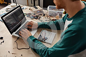 Engineer programming code of microchip on laptop