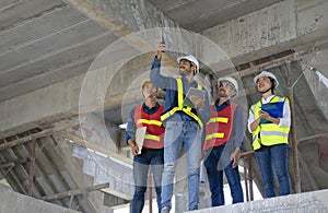 engineer project manager holding walkie talkie and tablet talking to work team on the building under construction