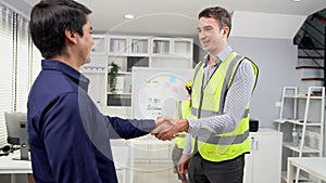An engineer with a protective vest handshake with an investor in his office