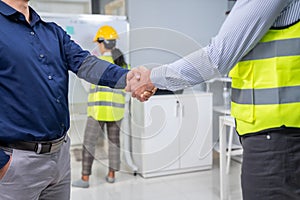 An engineer with a protective vest handshake with an investor in his office