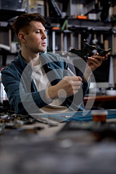 Engineer restores the laptop PC, examining disassembled parts of laptop. Electronic repair shop