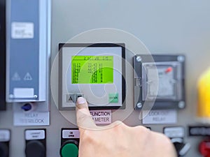Engineer`s hand check power meter parameter of voltage current watt hours in electric high voltage control building of power plan