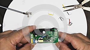 Engineer `s hand holding the tiny circuit board, reparing work or IIoT industry concept.