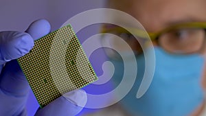 Engineer's hand holds sample of processor at technology plant