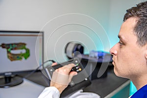 Engineer scans high-quality plastic component with 3D scanner, rotating platform using joystick photo