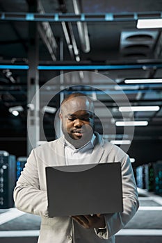 Engineer in server farm managing infrastructure systems, checking recovery plan