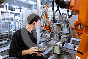 Engineer setting up automatic robot arms in smart factory, automotive industry, industrial concept