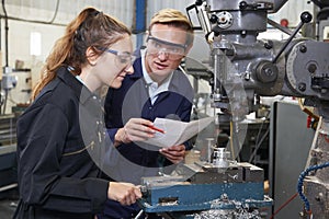 Engineer Showing Apprentice How to Use Drill In Factory