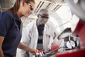 Engineer showing female apprentice how to operate machinery, close up