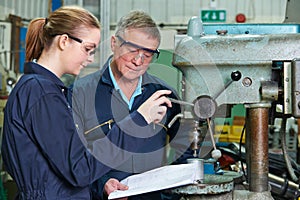 Engineer Showing Female Apprentice How To Use Drill In Factory