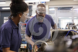 Engineer Showing Female Teenage Apprentice How To Use Lathe