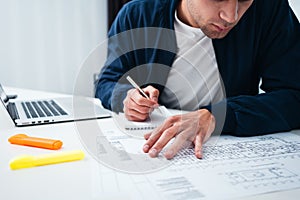 Engineer sitting at table and work with buliding drawing