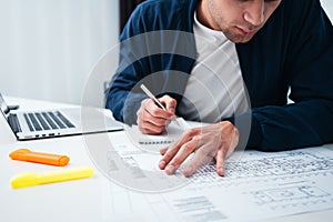 Engineer sitting at table and work with buliding drawing photo
