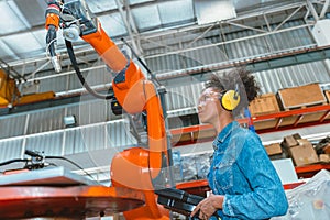 Engineer smart woman worker working programing robotic welding machine. Black teen girl work in advance modern factory