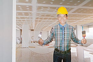 Engineer smile with hand holding Triangle trowel and paint brush wear yellow safety helmet plastic in building construction