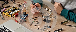 Engineer soldering microchip at table with laptop