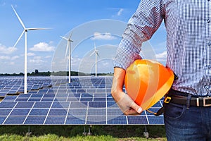 Engineer stand holding yellow safety helmet front solar photovoltaic and wind turbines generating electricity power station