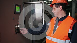 Engineer standing in front of industrial machine and going to press one buttons
