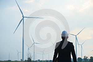 Engineer standing and hoding laptop with wind turbine photo