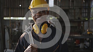 Engineer standing holding wrench on his shoulder at work in industry