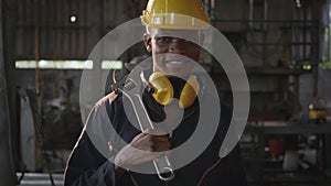 Engineer standing holding wrench on his shoulder at work in industry