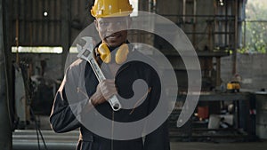 Engineer standing holding wrench on his shoulder at work in industry