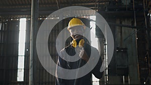 Engineer standing holding wrench on his shoulder at work in industry