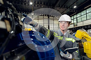 Engineer standing by robotic arm and operating machine in industry factory