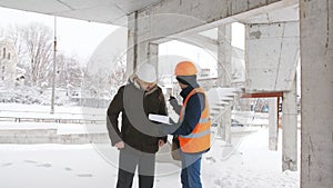 An engineer and superintendent communicate on the construction site in winter.