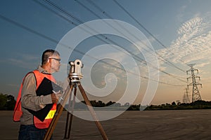 Engineer or surveyor working with theodolite equipment at at a field.