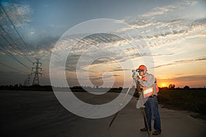 Engineer or surveyor working with theodolite equipment at a field.