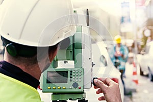 Engineer surveyor working with theodolite at road construction site