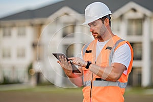 Engineer with tablet, building inspection. Portrait of builder man. Construction worker with hardhat helmet on