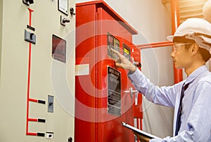 Engineer with tablet check red generator pump for water sprinkler piping and fire alarm control system.