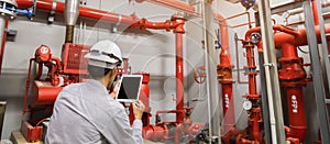Engineer with tablet check red generator pump for water sprinkler piping and fire alarm control system