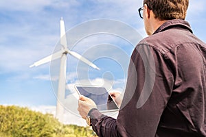 Engineer and tablet in wind power field working for renewable sustainable energy. Technician in industrial electricity generation.