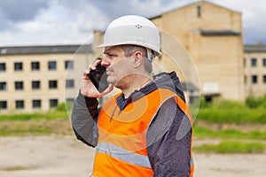 Engineer talking on cell phone near building