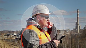 Engineer talking on the cell phone near factory