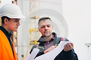 Engineer talking discussing with Architect working with blueprints for architectural plan, sketching a project.