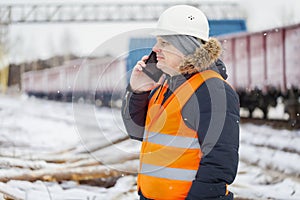 Engineer talking on the smartphone near the freight wagons