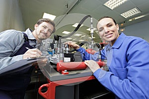 engineer teaching apprentice to use computerized lathe