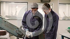 Engineer Teaching Apprentice To Use Grinding Machine