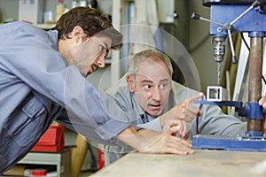 Engineer teaching apprentice to use milling machine