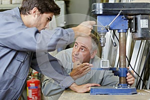 Engineer teaching apprentice to use milling machine