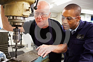 Engineer Teaching Apprentice To Use Milling Machine