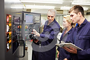 Engineer Teaching Apprentices To Use Computerized Lathe