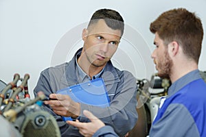 engineer teaching apprentices to use computerized metal processing machines