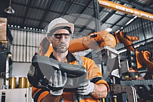 Engineer team service robot welding working in automation factory. Male worker operate robotic arm software hand controller in