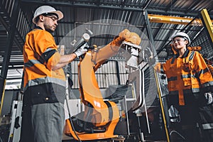 Engineer team service robot welding working in automation factory. People worker in safety suit work robotic arm software