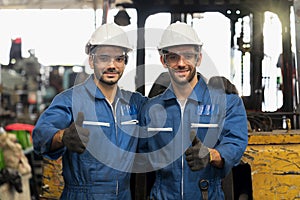 Engineer or technician Concept. Two Males mechanic with a blue uniform showing thumb up in factory